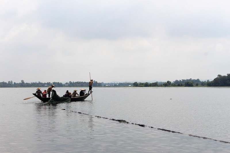 Fishermen on boat in flooded wetland