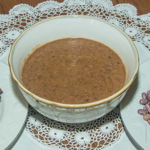 Bowl of fish-bean-vegetable soup on white lace tablecloth
